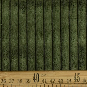 May include: Close-up of a dark green corduroy fabric with a ruler measuring 35 to 45 centimetres.