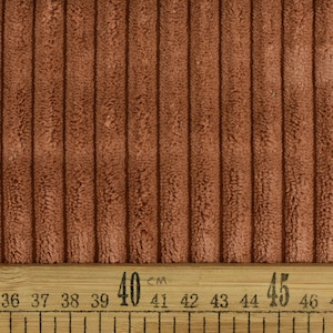 May include: Close-up of a brown corduroy fabric with a ribbed texture. A ruler with markings in centimetres is visible at the bottom of the image. The ruler shows measurements from 33 cm to 49 cm.
