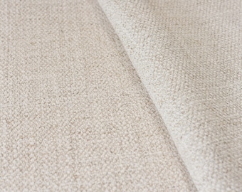May include: Close-up of a beige fabric with a textured woven pattern. The fabric is folded in half, showing the texture of the weave.