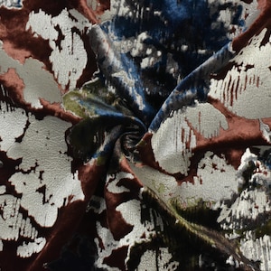 May include: Close-up of a fabric with a brown, blue and white abstract pattern. The fabric has a soft, velvety texture.