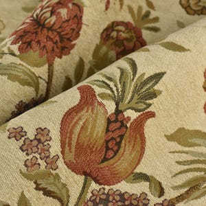 May include: Close-up of a beige fabric with a repeating floral pattern. The design features large, stylized flowers in shades of red, brown, and green, with intricate details. The fabric has a textured appearance.