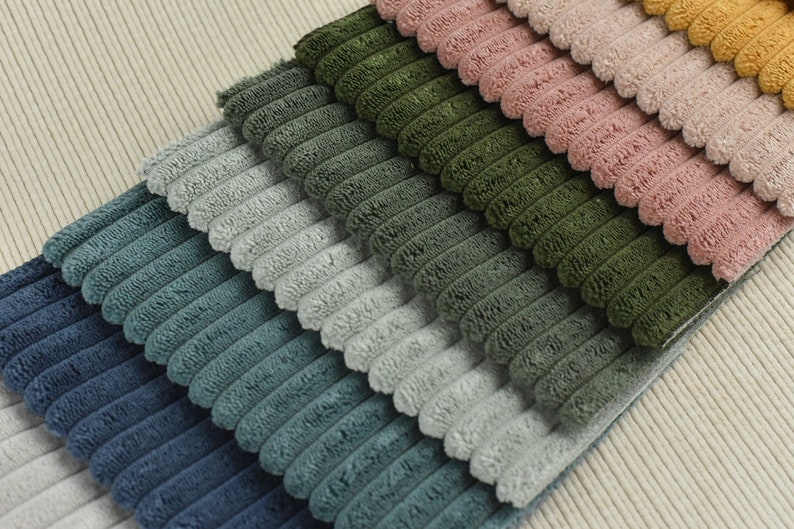 May include: A stack of different coloured corduroy fabrics. The fabrics are arranged in a gradient from dark blue to light yellow.