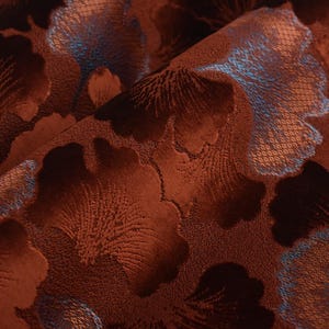 May include: Close-up of a brown fabric with a blue and brown floral pattern. The fabric has a textured, almost velvety surface.
