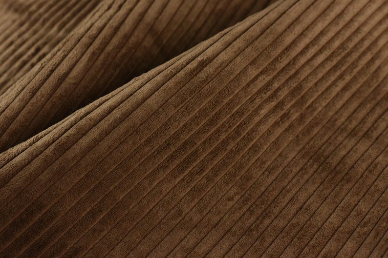 May include: Close-up of brown corduroy fabric with a subtle texture and a diagonal pattern.