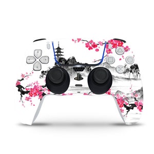 Può includere: Controller PlayStation 5 bianco con un design di ispirazione giapponese. Il controller presenta un paesaggio in bianco e nero con fiori di ciliegio rosa. Il controller ha joystick neri, pulsanti grigi e un accento blu.