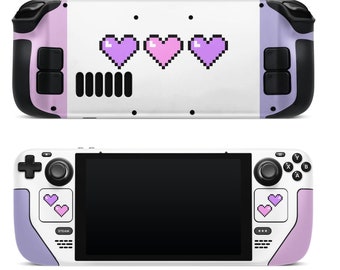 Könnte beinhalten: Eine weiße und violette Spielekonsole mit einem Pixel-Herz-Design. Die Konsole hat einen schwarzen Bildschirm und einen violett-weißen Controller.