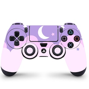 以下が含まれることがあります： 月と星のデザインが施された、紫とピンクのPlayStation 4コントローラー。コントローラーは、PlayStationロゴの入った黒い前面プレートが付いています。