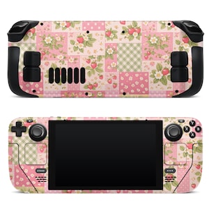 Pode incluir: Console de jogos portátil com um design de patchwork rosa e branco com morangos e padrões florais. O console tem botões de controle pretos e uma tela preta. A palavra "STEAM" é visível na frente.