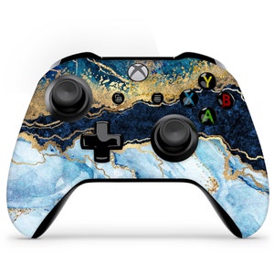 May include: A black Xbox controller with a blue and gold marble design. The controller has a black d-pad, black buttons, and black triggers.