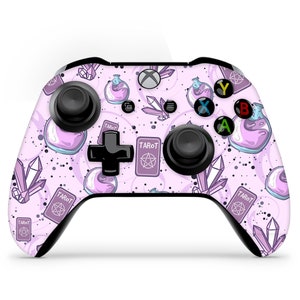 Pode incluir: Um controle Xbox rosa e preto com um design de tarot e poções. O controle apresenta um design de carta de tarot roxo e branco com a palavra "Tarot" impressa nele. O controle também apresenta um design de frasco de poção com líquido roxo e uma rolha branca.