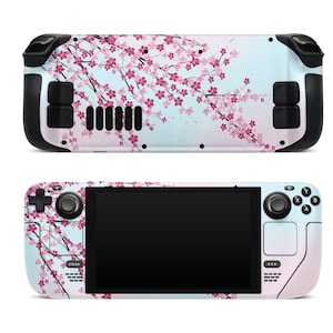 Op de afbeelding: Een witte en blauwe gameconsole met een roze kersenbloesemontwerp. De console heeft een zwarte rand en knoppen. De console bevindt zich in een liggende oriëntatie.