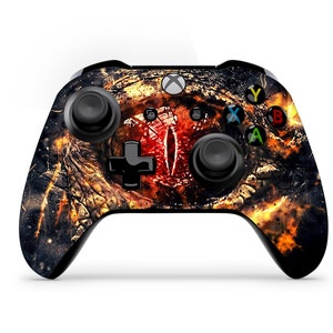 May include: A black Xbox controller with a custom skin featuring a fiery red eye with a black and gold background.