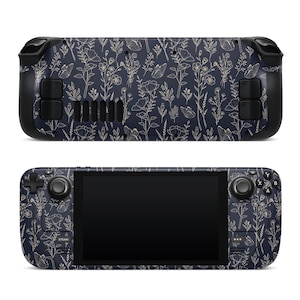 Pode incluir: Um console de jogos portátil com um design floral azul marinho. O console apresenta uma tela preta, botões e joysticks. O padrão floral inclui contornos brancos e dourados de flores e folhas.