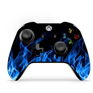 May include: A black Xbox controller with a blue flame design. The controller has a black d-pad, black buttons, and black triggers.