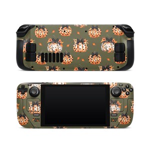May include: A handheld gaming console skin featuring a repeating pattern of orange pumpkins with black bows and floral accents on a green background. The console has black buttons and a black screen.