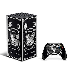 Op de afbeelding: Een zwarte Xbox Series X console en controller met een zwart-wit ouija bord ontwerp met een kat en de woorden "YES OUIJA NO".