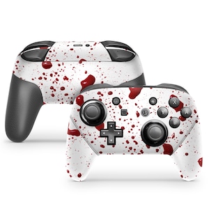 Könnte beinhalten: Ein weißer Nintendo Switch-Controller mit einem roten Blutfleckendesign. Der Controller hat einen schwarzen Griff und schwarze Tasten.