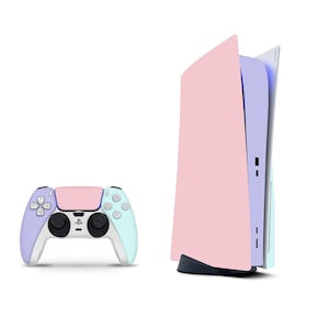 May include: A pastel-coloured gaming console and controller set. The console is primarily pink with a light blue and white accent. The controller features a matching colour scheme of pink, light blue, and lavender. The set is designed for gaming.
