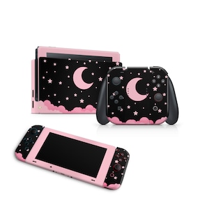 May include: Pink and black Nintendo Switch console with a moon and stars design. The console has a pink and black Joy-Con controller with a moon and stars design.
