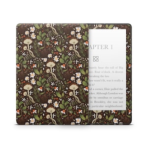 Puede incluir: Una funda para lector electrónico Kindle Paperwhite de color marrón y verde con un diseño de hongo blanco. La pantalla muestra el texto "CAPÍTULO 1" y un breve extracto de un libro.