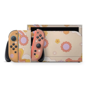 Peut inclure: Une console Nintendo Switch et des manettes Joy-Con avec un motif floral rétro. Les manettes sont orange et corail, et la console a un fond beige avec des fleurs orange, roses et jaunes.