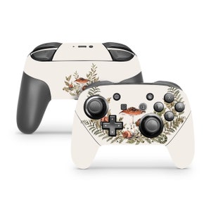 May include: A white Nintendo Switch controller with a custom skin featuring a watercolor design of mushrooms, ferns, and snails on a cream background.