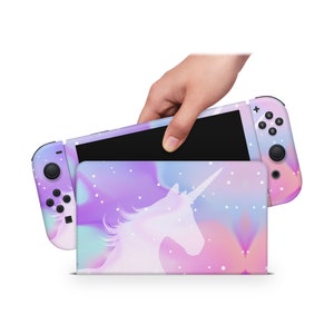 May include: A pink, purple, and blue Nintendo Switch console with a unicorn silhouette design. The console is closed and has a white background with white stars.