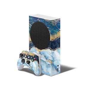 May include: A white gaming console with a blue and gold marble design skin. The console has a black speaker grille. A matching blue and gold marble design controller is included.