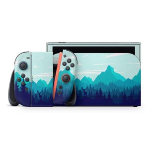 Puede incluir: Una consola Nintendo Switch y mandos Joy-Con con un diseño de paisaje de montañas y bosques. Los mandos tienen una combinación de colores azul y verde azulado con detalles en naranja. La consola tiene un diseño a juego.
