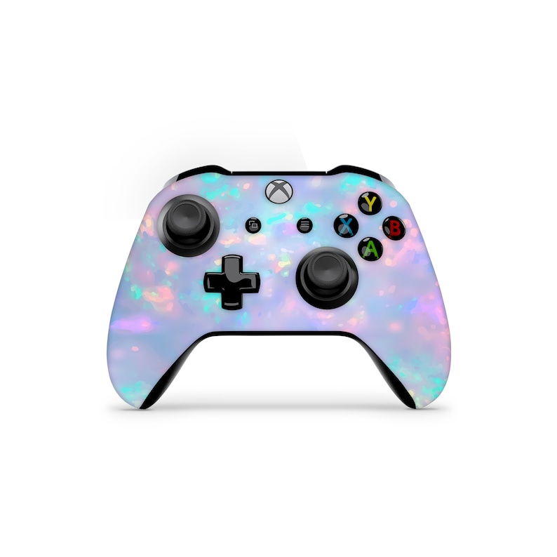 Puede incluir: Un mando Xbox blanco con un patr&oacute;n de &oacute;palo iridiscente azul claro. El mando tiene botones negros y una cruz direccional negra.