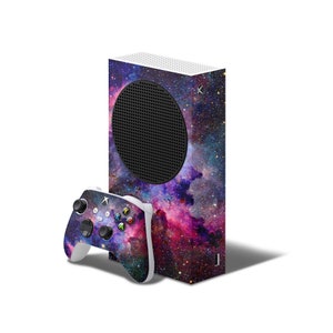 May include: A white Xbox Series X console with a galaxy-themed skin. The console has a black circular vent on the front. A matching galaxy-themed controller is included.
