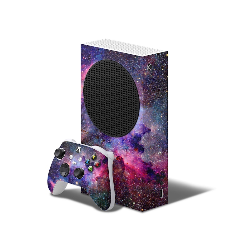 May include: A white Xbox Series X console with a galaxy-themed skin. The console has a black circular vent on the front. A matching galaxy-themed controller is included.