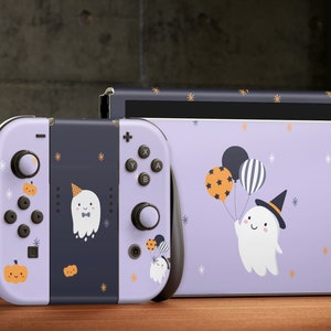 May include: A purple and black Nintendo Switch console and controller with a Halloween-themed design featuring ghosts, pumpkins, and stars.
