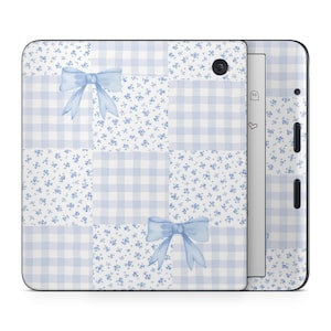 May include: An e-reader cover with a light blue and white patchwork design. The cover features gingham squares, floral patterns, and watercolour bows. The e-reader has a black power button and volume controls.