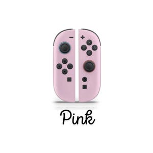 May include: Two pink game controllers with black buttons and joysticks. The controllers are displayed side by side, with the word "Pink" in cursive script beneath. The design is sleek and modern.