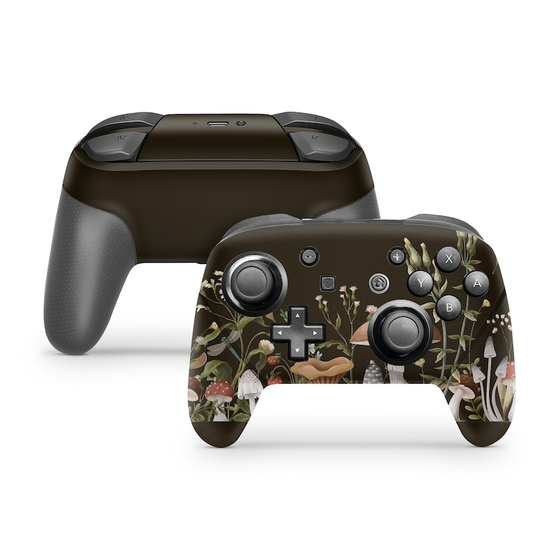 May include: A black Nintendo Switch controller with a floral and mushroom design. The controller has a dark brown background with a variety of flowers, mushrooms, and other botanical elements in shades of pink, white, and green.