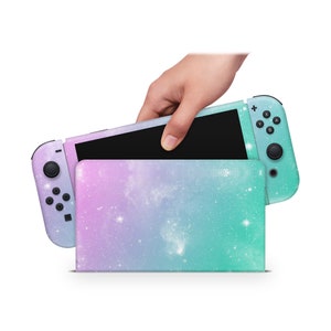 Può includere: Una skin per console Nintendo Switch a tema galassia turchese e viola con un supporto abbinato. La console è chiusa e il supporto è aperto.