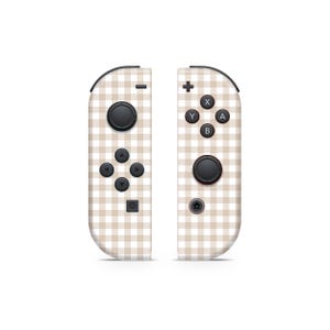 Op de afbeelding: Een paar Nintendo Switch Joy-Con-controllers met een wit en bruin gingham-patroon. De controllers hebben zwarte knoppen en een zwarte analoge stick.