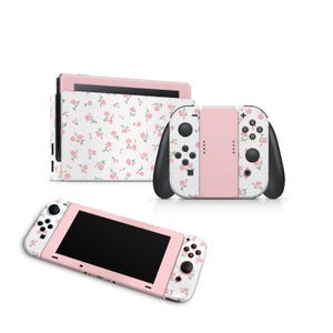 Pode incluir: Console Nintendo Switch rosa com um padrão floral. O console é mostrado com os controladores Joy-Con conectados.