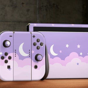 May include: A purple Nintendo Switch console and matching Joy-Con controllers with a moon and stars design. The design features white clouds and stars on a lavender background.