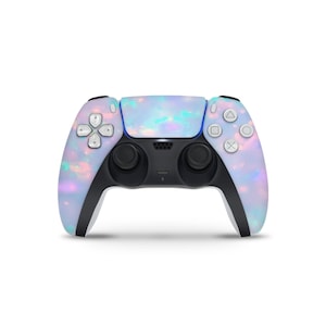 May include: A PlayStation 5 controller with a pearlescent, iridescent finish. The controller features a light blue, pink, and purple color scheme with black accents. The buttons and joysticks are black, and the directional pad and action buttons are white.