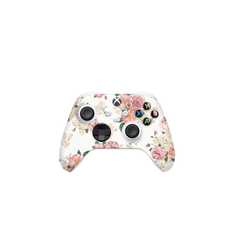 May include: White Xbox controller with a floral design featuring pink and white flowers. The controller has black buttons and a white background.