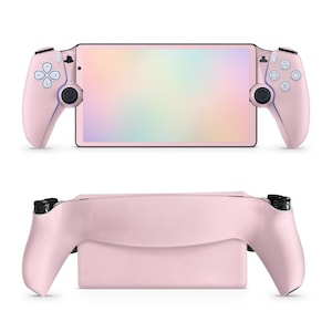 May include: A pink handheld gaming console with a rectangular screen displaying a rainbow gradient. The console has pink controllers on each side with blue accents and black joysticks. The bottom view shows the console's back and the controller grips.