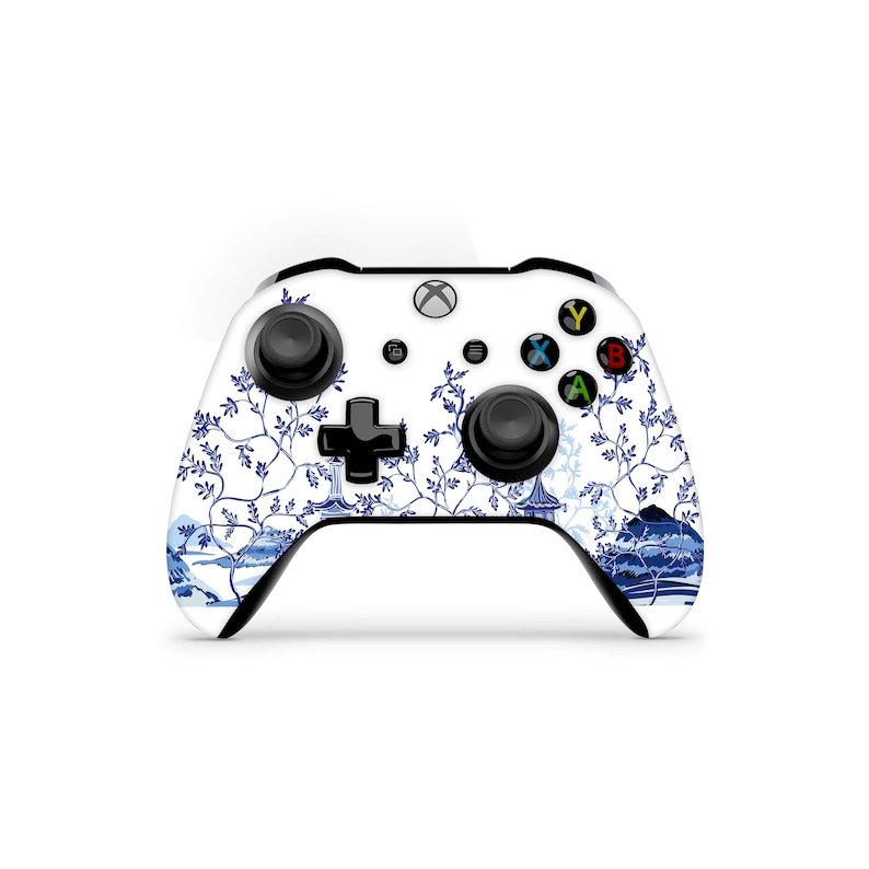 May include: A white Xbox controller with a blue and white floral design. The controller has black buttons and a black D-pad.