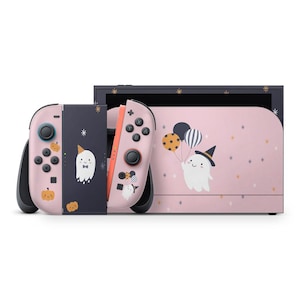 May include: A pink and navy blue Nintendo Switch console with a Halloween theme. The console features a ghost and pumpkin design. The Joy-Cons are pink and navy blue with black buttons. The screen has a pink background with a ghost holding balloons.