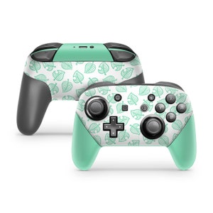 May include: A pair of green and white Nintendo Switch Joy-Con controllers with a leaf pattern. The controllers are shown from the front and side.