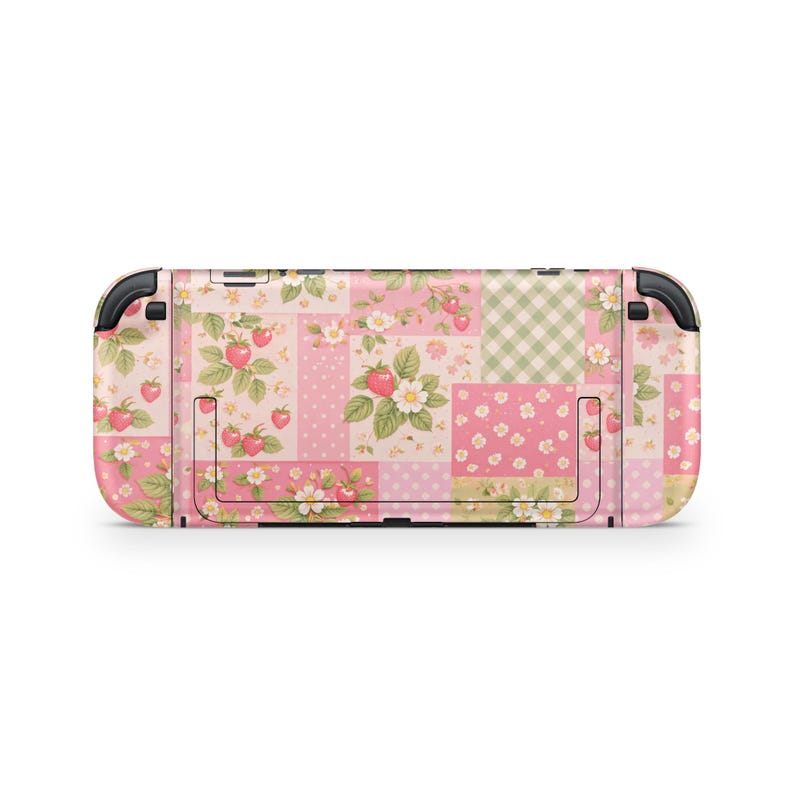 May include: A pink and white patterned Nintendo Switch console skin. The design features a patchwork of floral and strawberry patterns, with a gingham and polka dot pattern. The skin has black accents on the sides.