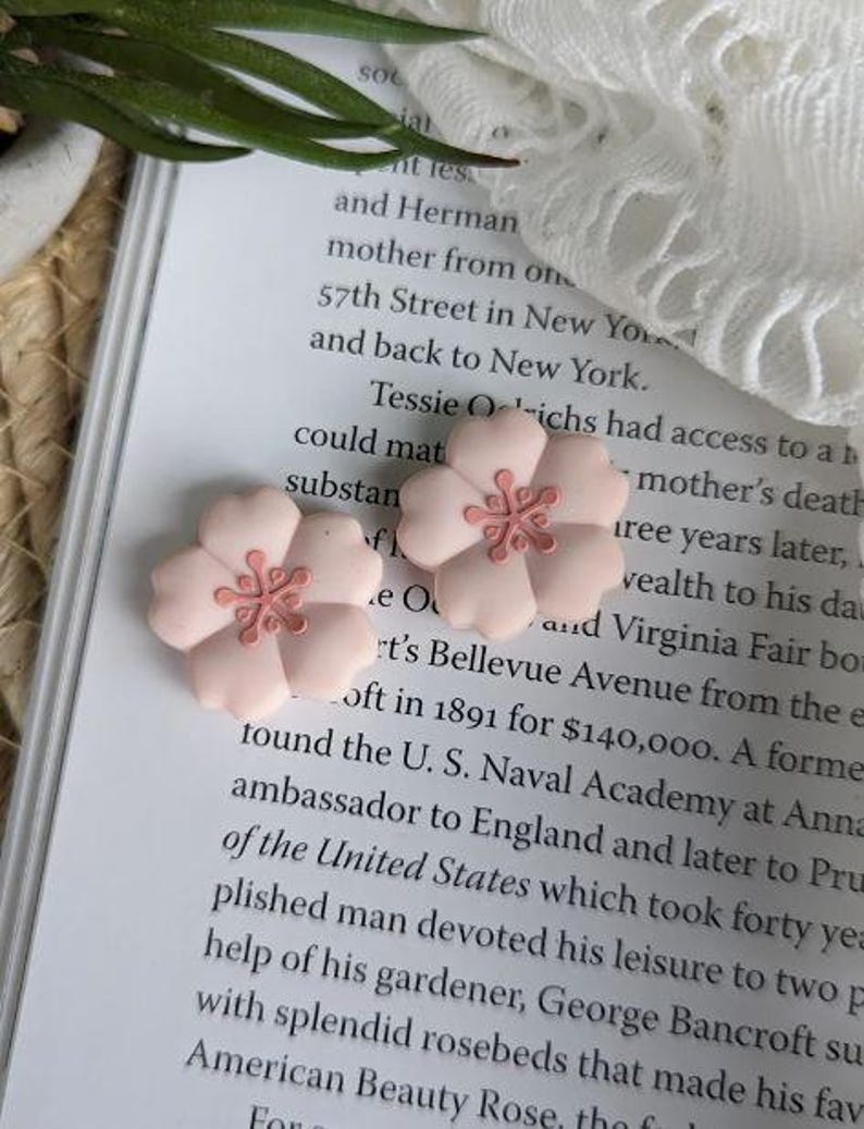 May include: Two pink ceramic flower hair clips with a light pink center. The flowers have a 3D design and are perfect for adding a touch of whimsy to any hairstyle.