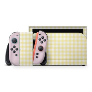 May include: A Nintendo Switch console and Joy-Con controllers with a yellow and white gingham pattern. The Joy-Cons are pink with black buttons and joysticks. The console dock also features the same gingham design.