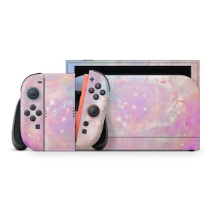 Op de afbeelding: Een Nintendo Switch-console en Joy-Con-controllers met een skin met een galaxiethema. De skin heeft een mix van roze, paarse en witte kleuren met een sterrenhemel-effect. De controllers zijn zwart met gekleurde knoppen.